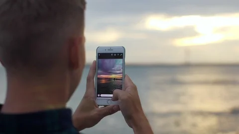 Back view of a man standing on the pier, enjoying sunset over sea and making Stock Footage 97450231