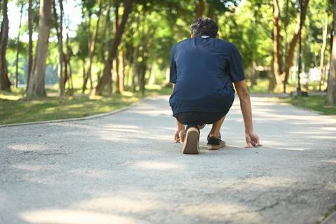 Back view of man in a starting position on the ground, ready to sprint. Goals Stock Photos