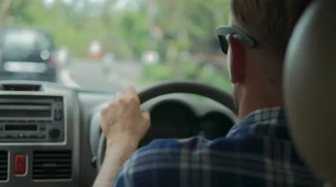 Back view of man with sunglasses driving a car on road with green trees Stock Footage 68030254