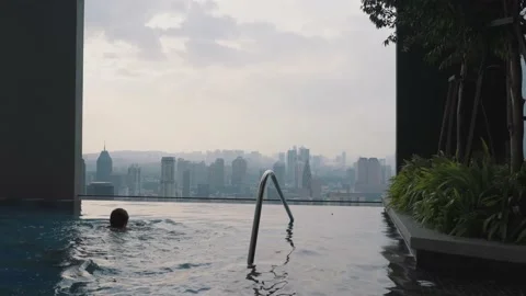 Back view of man swim and relax on the edge of the roof top swimming pool in Stock Footage 231786679