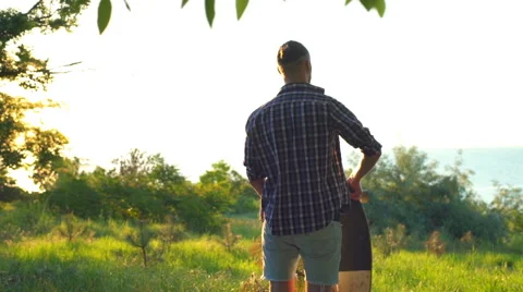 Back view man takes longboard on shoulders in park slow motion Stock Footage 64522376