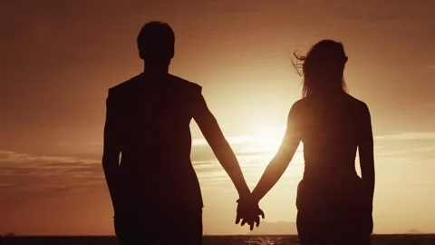 Back view, a man takes a woman's hand against the backdrop of an orange sunset Stock Footage 250385145