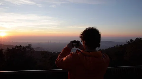 Back view of a man taking pictures at sunrise Stock Footage 104123564