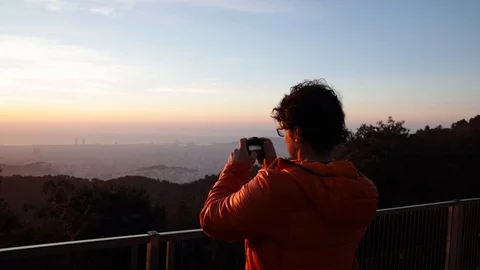 Back view of a man taking pictures at sunrise Stock Footage 104123569