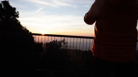 Back view of a man taking pictures at sunrise Stock Footage 104123570