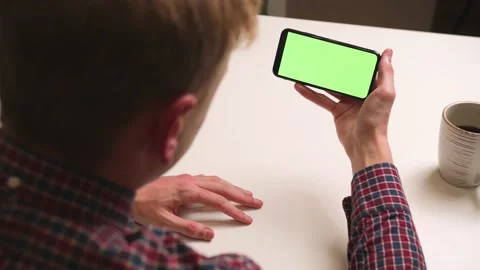Back View. Man using phone with green screen chromakey, Surfing internet Stock Footage 146598100
