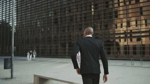 Back view of man walking and sitting on ... | Stock Video | Pond5
