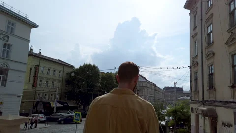  Back view man walking down the street and talking by smartphone Video stock 136136242