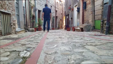 Back view of man walking in Penna in Teverina medieval alley Видео 279908291