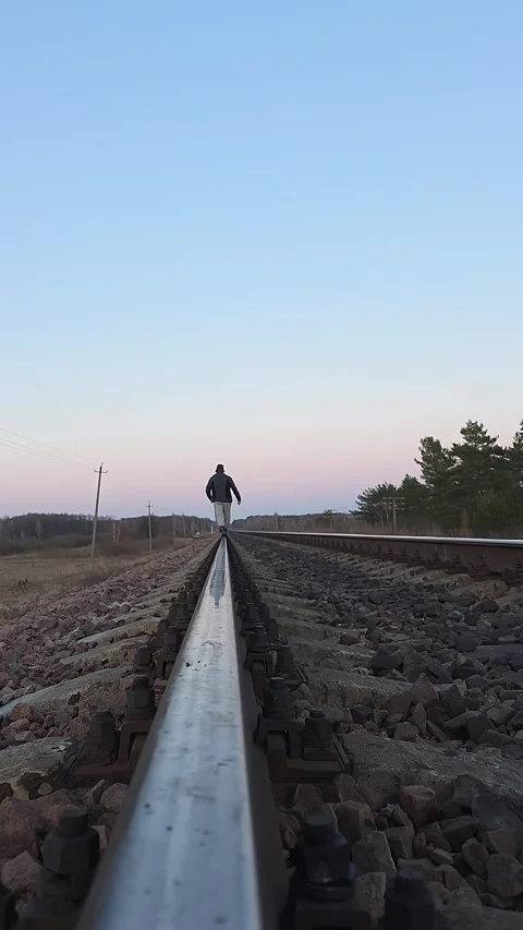 Back view of a man walking on a railway track at sunset. Silhouette of a pe.. Vídeos de archivo 333790947