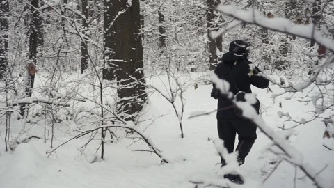 Back view on the man walking in the winter forest with his smartphone to shoot a Stock Footage 101119913