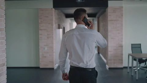 Back view man walks and talks use smartphone Stock Footage 168323382