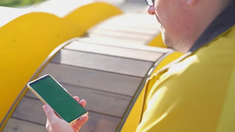 Back view of man watch smart phone with green screen and browsing online outside Stock Footage 168201089