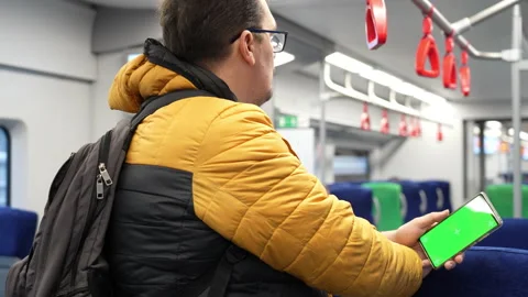 Back view of man watch smart phone with green screen and browsing online in Stock Footage 168231569