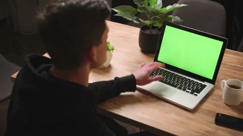 Back view of man waving hand on camera laptop green screen chromakey, man has Stock Footage 148384356