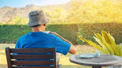 Back view of man wear hat drink tea or coffee at summer garden. Carefree ma.. Stock Photos