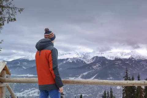 Back view of man wearing red jacket looking away against idyllic landscape of Stock Photos