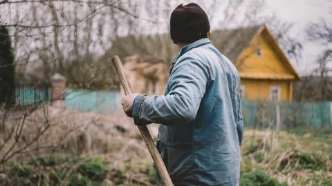 Back view of man worker with shovel on the farm rancho. Male Gardener digging Stock Photos