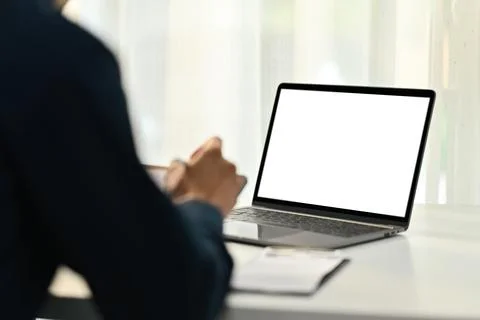 Back view of man worker sitting at office desk with blank screen laptop computer Foto stock