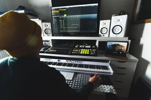 Back view of a man working at a desk on music production at home studio Stock Photos