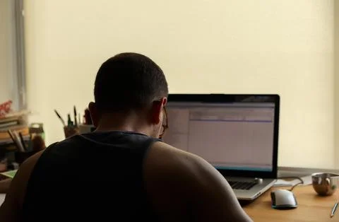 Back view of a man working on a laptop at his desk in a home office, concep.. Stock Photos