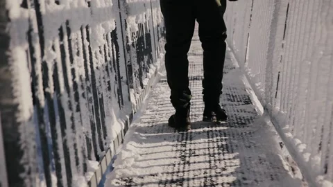 Back view of man's legs walking on Peak Walk bridge on snowy day in winter Stock Footage 226201702