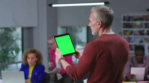 Back view of mature man holding digital tablet with green screen standing in Stock Footage 189229624