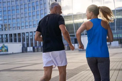 Back view of middle aged couple in sportswear full of energy jogging together in Stock Photos