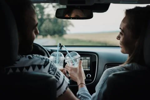 Back view on middle-aged couple sitting inside car and drinking coffee, man and Stock Photos