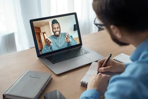 Back view of millennial man watching online training or course on laptop Stock Photos