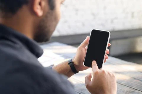 Back view mixed-race guy is using smartphone device with a blank screen Stock Photos