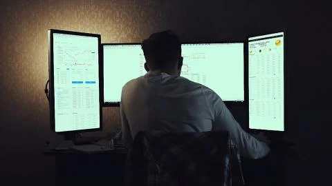 Back view of modern programmer sitting and writing code in dark room. Stock Foto stock