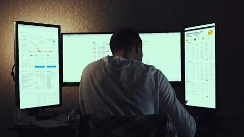 Back view of modern programmer sitting and writing code in dark room. Stock Stock Photos