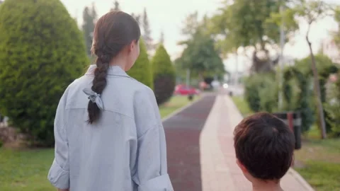 Back view of Mother and son walking holding hands along the alley Stock Footage 201113865