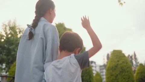 Back view of Mother and son walking holding hands along the alley Stock Footage 201215946