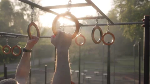 Back View of Muscular American Guy Doing Gymnastic Ring Workout on Outdoor Field Stock Footage 287902772
