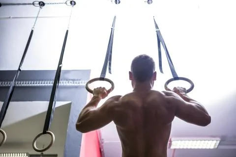 Back view of muscular man doing ring gymnastics Stock Photos