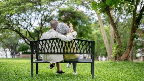 Back view of old man hugging woman and her pointing finger while sitting to.. Stockfoto's