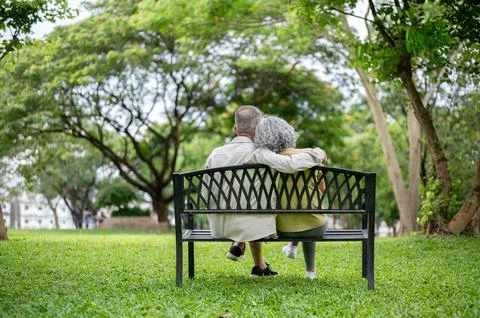 Back view of old man hugging a woman shoulder as sitting leaning against ea.. Stock Photos