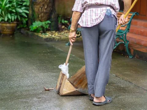 Back view of old man using broom sweep garbage at sidewalk Stock Photos