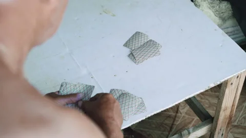 Back view of old men with bare torso, playing cards on old wood table outside Stockbeeldmateriaal 134421325