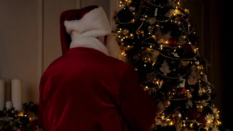 Back view old Santa Claus decorates Christmas tree with New Year decorations Stock Footage 165382237