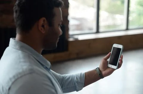 Back view over the shoulder at the empty smartphone screen in hand of Indian man Stock Photos