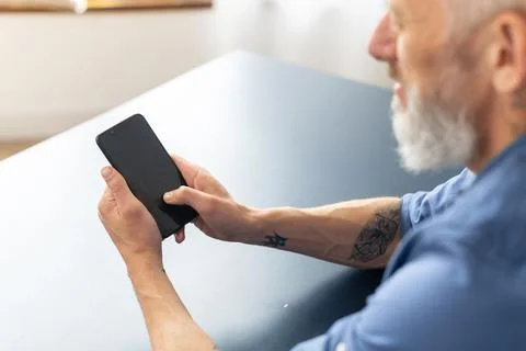Back view over shoulder of senior man at the smartphone with blank screen Stock Photos