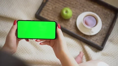 Back view over shoulder of young girl using smartphone with green screen sitting Stock Footage 142044786