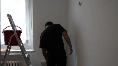 Back View of Painter Applying White Paint to Wall with Roller Tool in Brigh.. Vídeo Stock 347724438