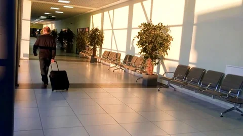 Back view of passenger walking and carrying a suit case in an airport Stock Footage 84799465