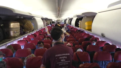 Back view of passengers entering an aeroplane, taking their sits and putting Stock Footage 155948032