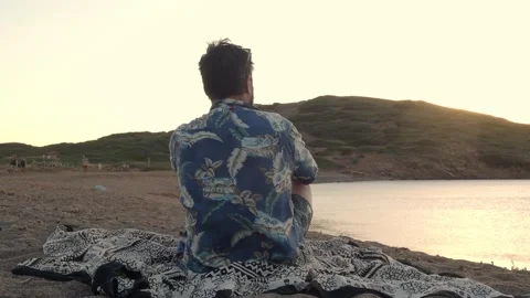 Back view of a pensive man sitting on the beach during a sunset. Stock Footage 166977549