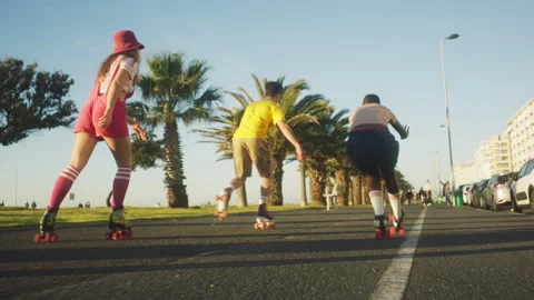 Back view of people rollerskating next to the palm trees Stock Footage 279339558